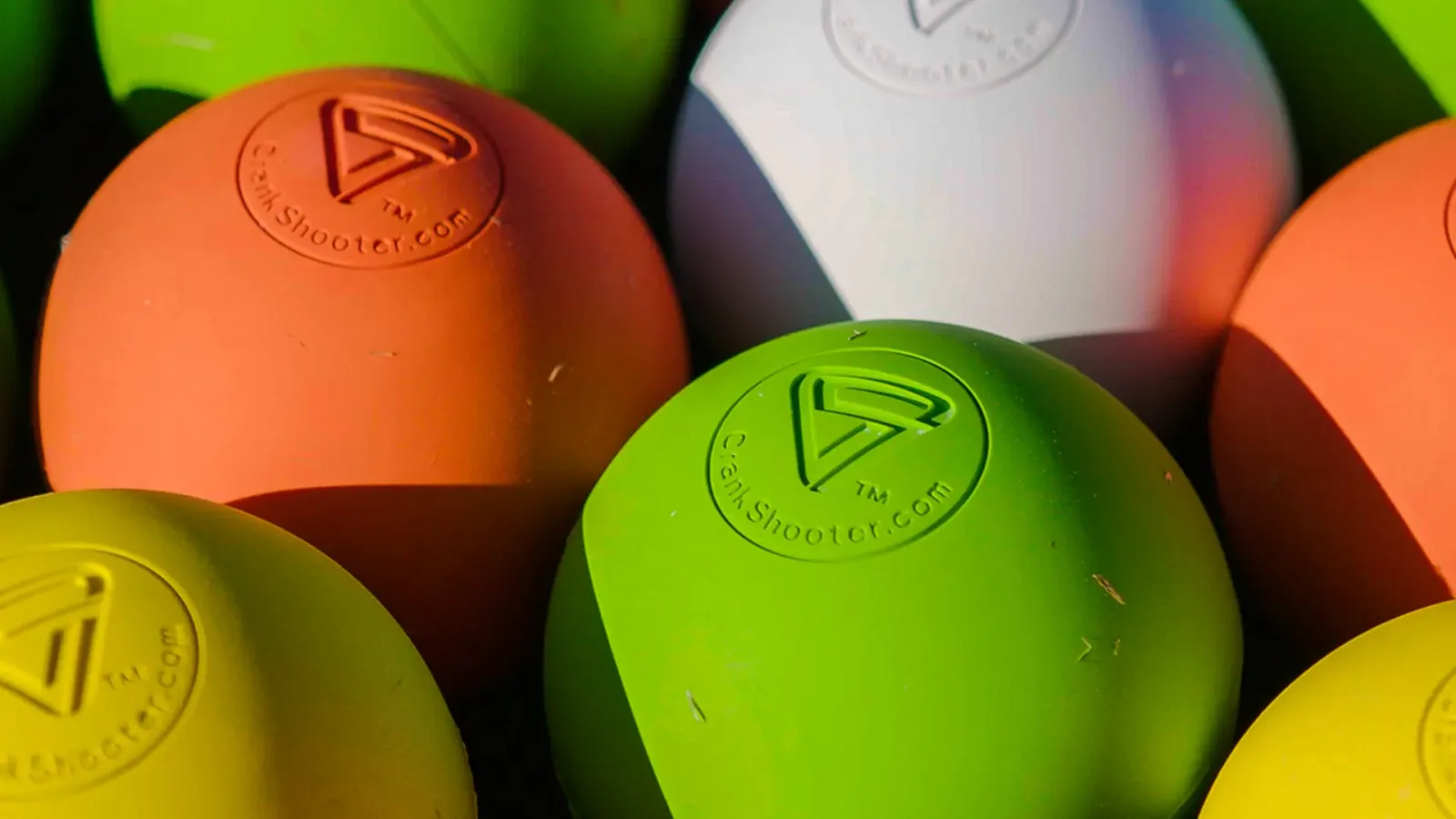 Orange, green, white, and yellow Crankshooter lacrosse balls