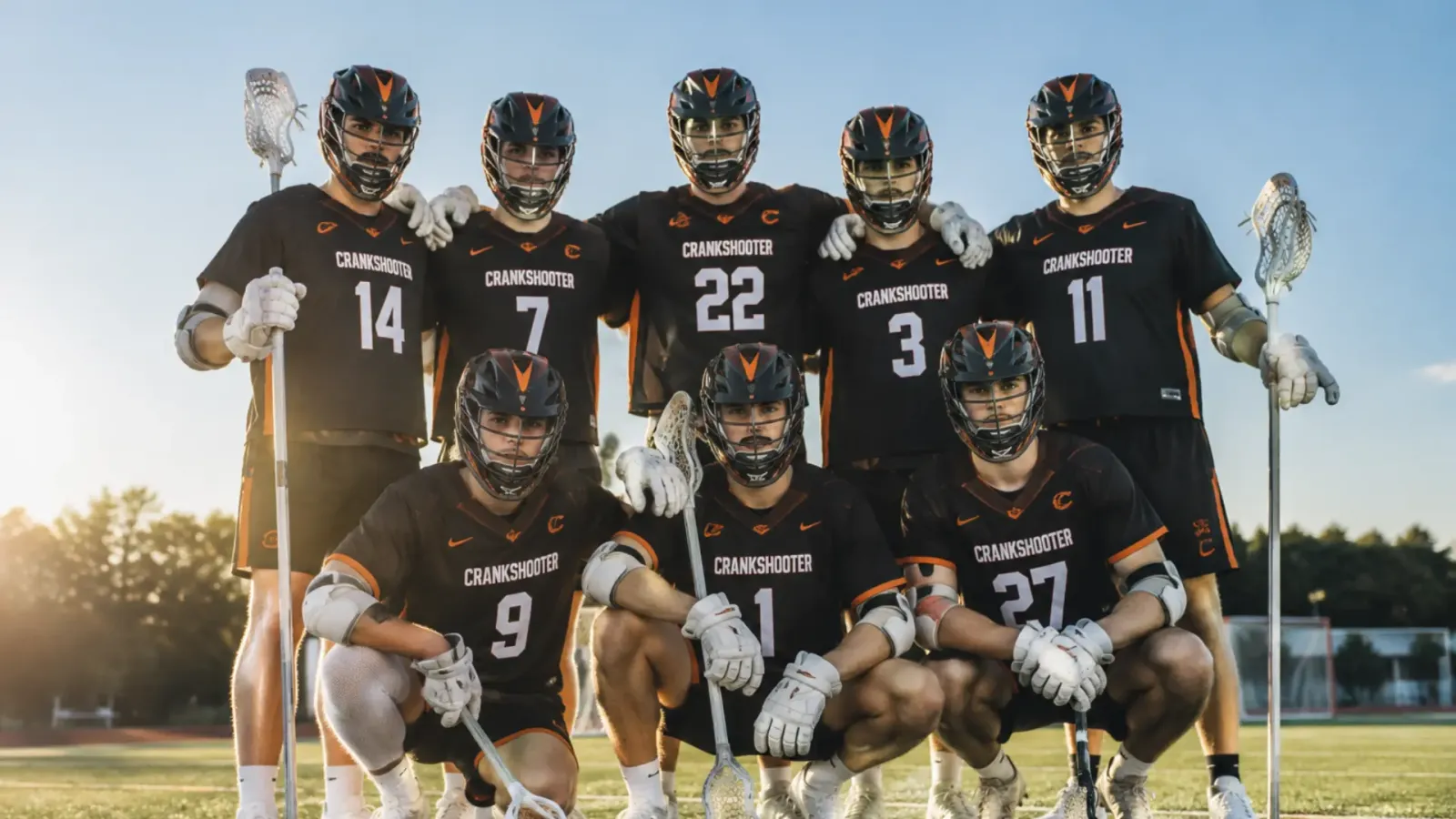 Crankshooter lacrosse team posing in black and orange uniforms on the field